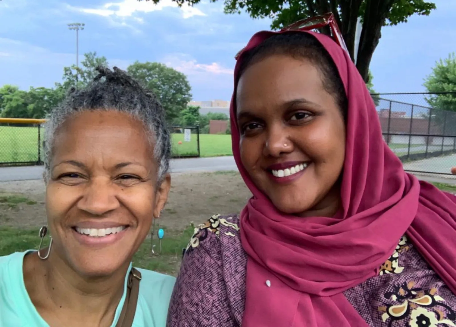 Two community members outdoors on a summer evening